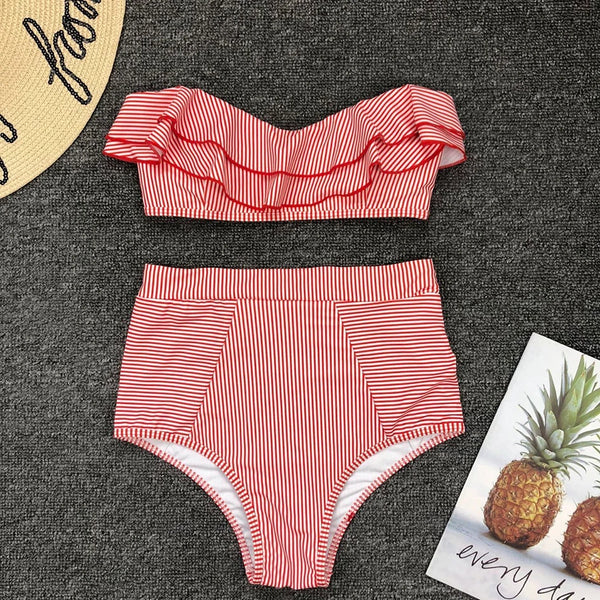 Red and white striped bikini set on a dark textured surface with a pineapple-themed card.