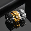 Three metallic rings in black, gold, and silver on a reflective surface.
