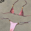 Pink bikini set with beaded straps on a sandy surface