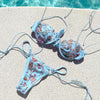 Blue floral bikini set on a poolside ledge.