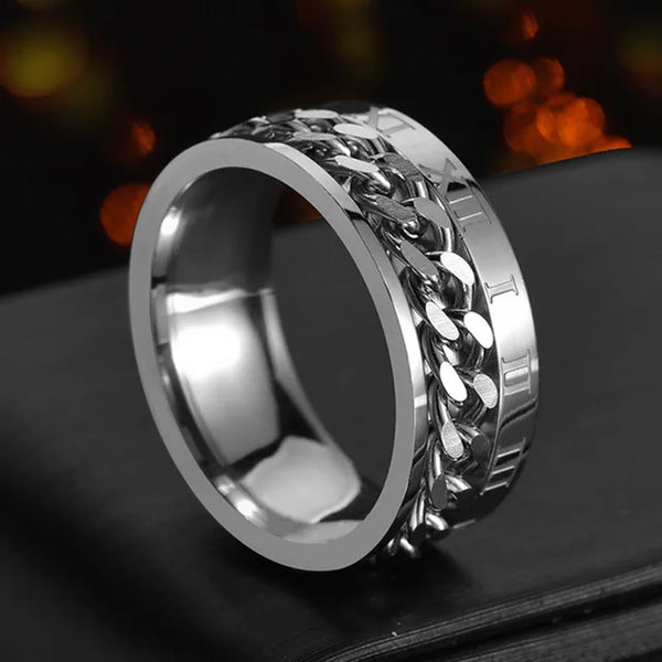 Silver chain ring on a dark surface with blurred lights in the background