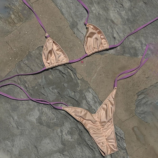 Beige bikini set with purple straps on a stone surface