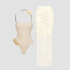 Beige swimsuit with floral details and matching fringed skirt on a light gray background