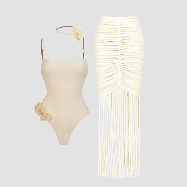 Beige swimsuit with floral details and matching fringed skirt on a light gray background