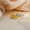Gold and silver rings with engraved text on a soft fabric background