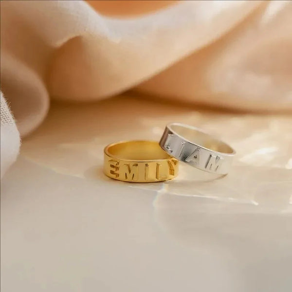Gold and silver rings with engraved text on a soft fabric background