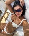 Woman in a white bikini and sunglasses lounging on a towel