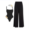 Black swimsuit with floral details and black wide-leg pants on a white background