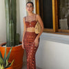 Woman in a brown outfit standing next to a cactus plant indoors.