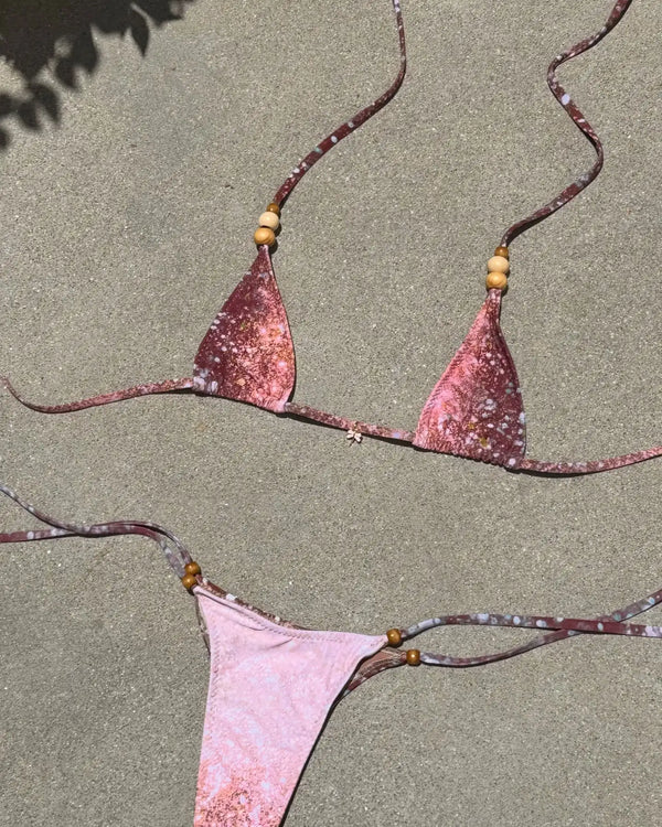 Pink bikini set with beaded straps on a beige background