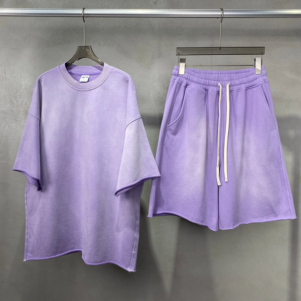 Purple t-shirt and shorts set hanging on a rack against a gray background