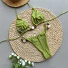 Green bikini set on a woven mat with flowers on a gray background