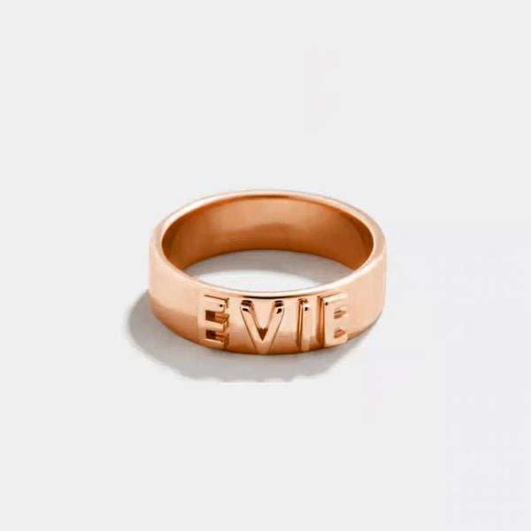 Rose gold ring with 'EVIE' engraving on a light gray background