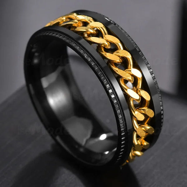 Gold chain ring with black band on a dark surface