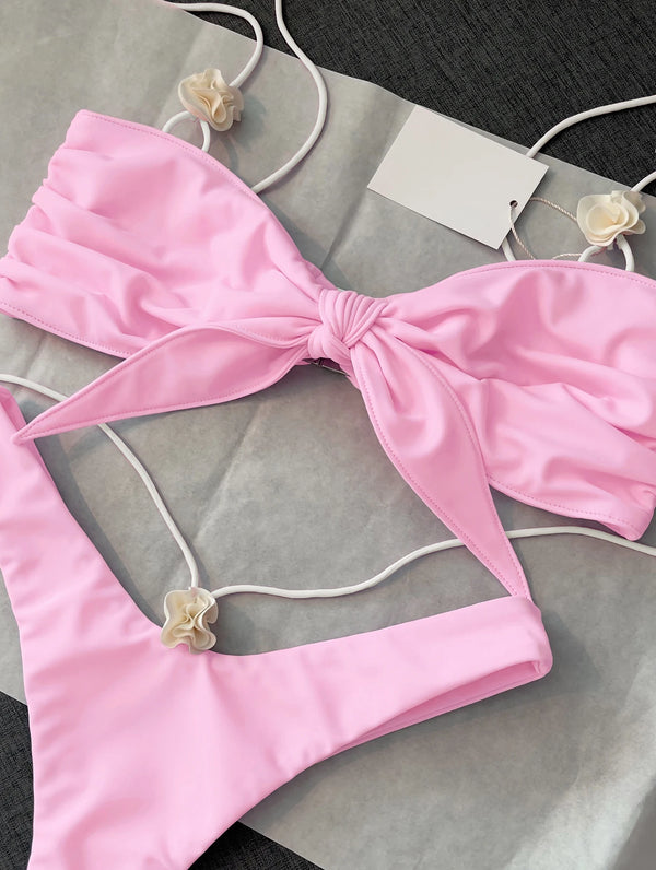 Pink bikini set with a bow detail on a gray surface