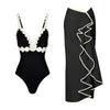 Black swimsuit with white scalloped edges and black skirt with white trim on a white background