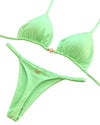 Green bikini set with a brand tag on a textured surface