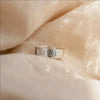 Silver ring with engraved name on beige fabric