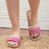 Pink and beige sandals worn on feet with a white textured background