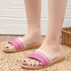 Pink sandals worn on feet standing on a woven mat.