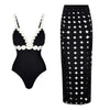 Black swimsuit with white accents and black skirt with geometric pattern on a white background
