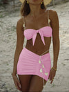 Woman wearing a pink bikini with heart details on a beach.