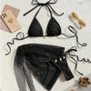 Black bikini set with matching cover-up on a light surface with accessories.