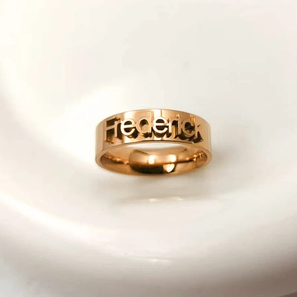 Rose gold ring with engraved name on a light gray background