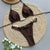 Brown bikini set with pearl details on a woven mat with flowers.
