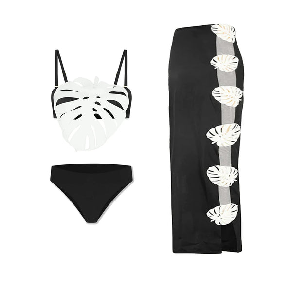 Black bikini set with white leaf patterns and a black skirt with similar designs on a white background.