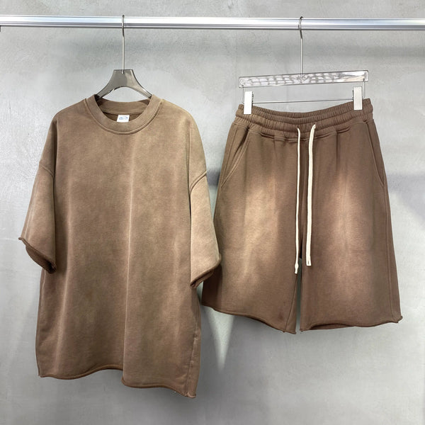 Brown t-shirt and shorts set on hangers against a gray background