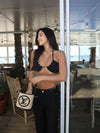 Woman in a black bikini holding a Louis Vuitton bag in an outdoor setting.