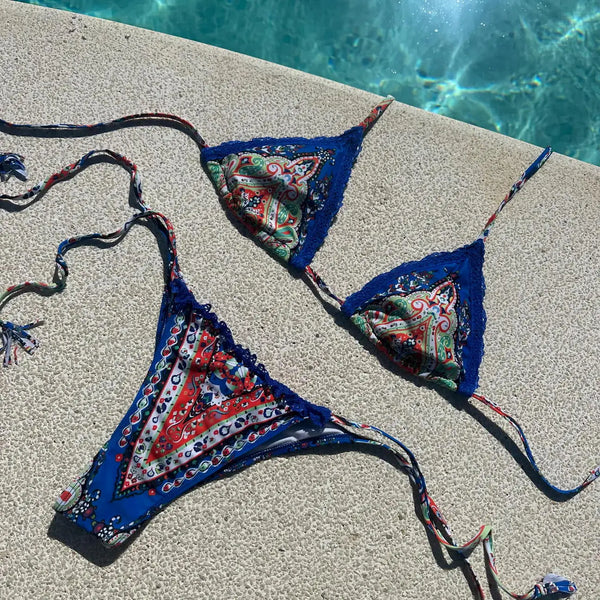 Colorful bikini set on a poolside ledge with water in the background