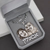 Silver necklace with engraved faces and Hebrew text in an open jewelry box.