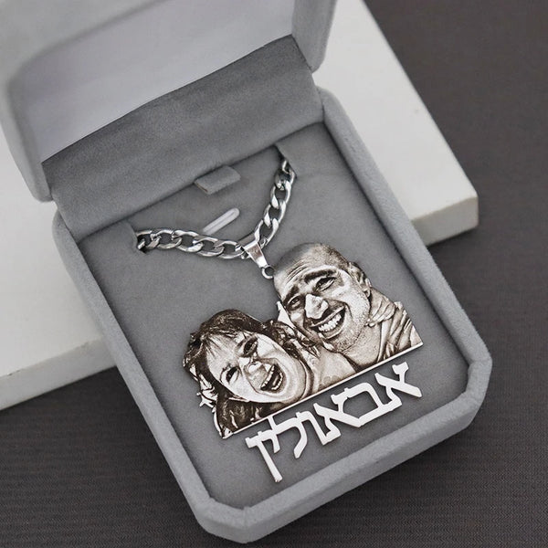 Silver necklace with engraved faces and Hebrew text in an open jewelry box.