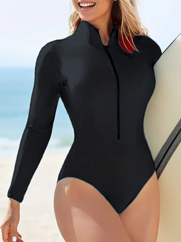 Person wearing a black wetsuit with a zipper on a beach