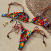 Colorful bikini set with matching accessories on a textured surface