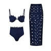 Navy blue bikini set with high-waisted bottoms and a matching skirt with white pattern on a white background.
