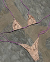 Beige bikini set with purple straps on a stone surface