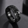 Black metal ring with intricate design on a dark surface
