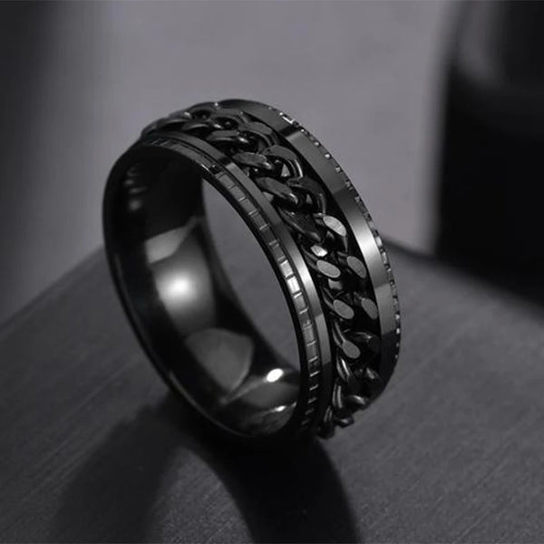 Black metal ring with intricate design on a dark surface