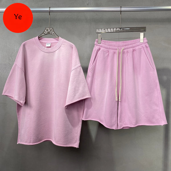 Pink t-shirt and shorts set on hangers against a gray background with 'Ye' label.