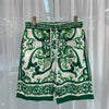 Green and white patterned shorts on a hanger against a white curtain background