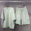 Light green t-shirt and shorts set on hangers against a gray background