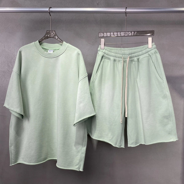 Light green t-shirt and shorts set on hangers against a gray background