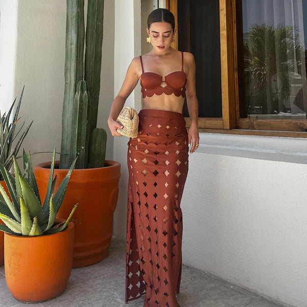 Woman in a brown outfit standing next to potted plants indoors