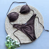 Brown bikini set on a woven mat with a light blue background