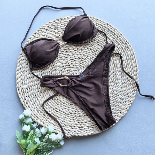 Brown bikini set on a woven mat with a light blue background