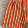 Close-up of a ball of yarn with orange and beige stripes.