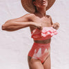 Woman wearing a red and white striped bikini with a straw hat on a light background